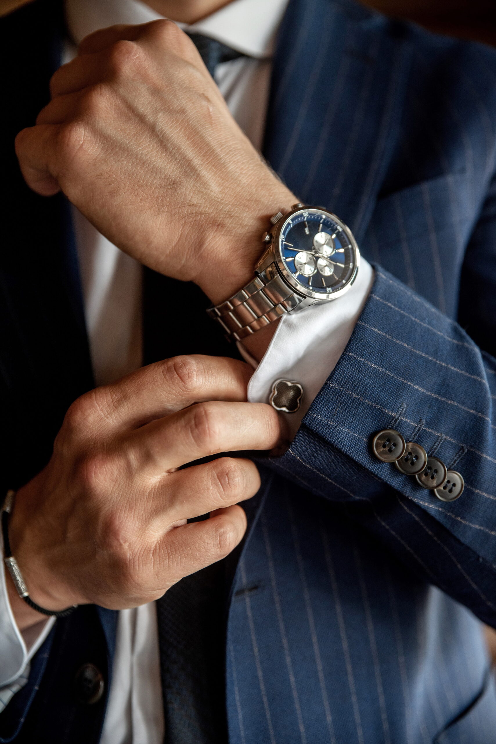 White man checking cufflinks with wristwatch close up<br />
