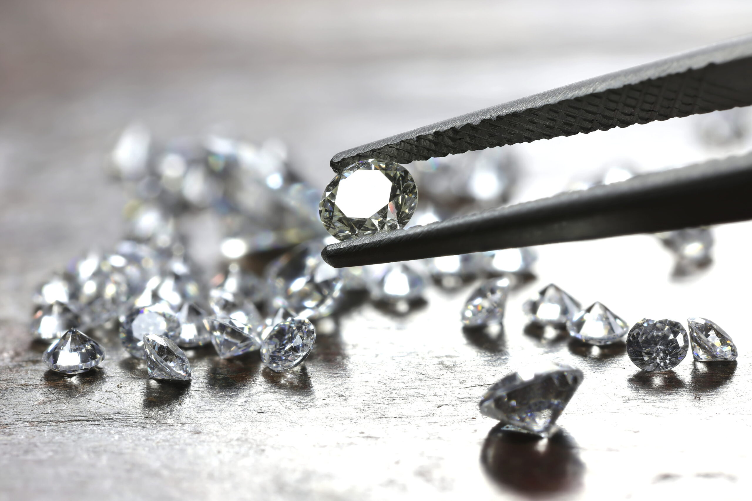 brilliant cut diamond held by tweezers<br />
