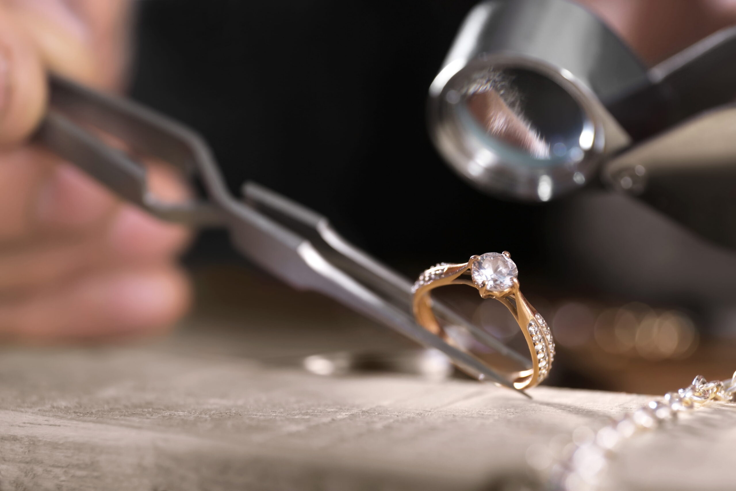 brilliant cut diamond held by tweezers
